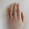 An image of a purplish black spinel on a hand to give perspective of its size and appearance.