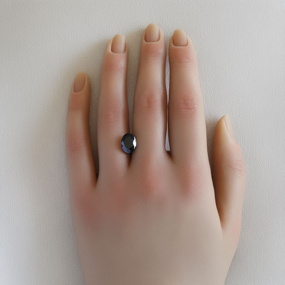 An image of a purplish black spinel on a hand to give perspective of its size and appearance.