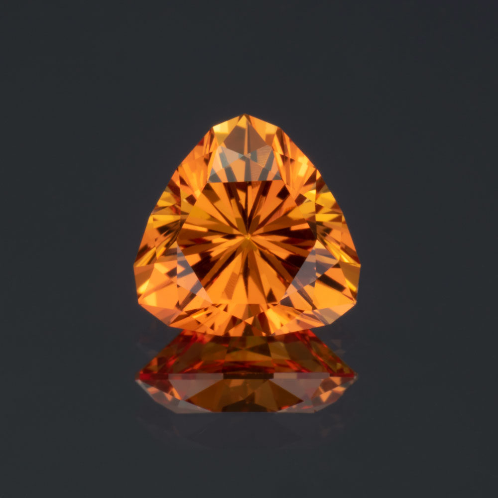 A closeup image of a brilliant orange trillion cut lab-created sapphire.