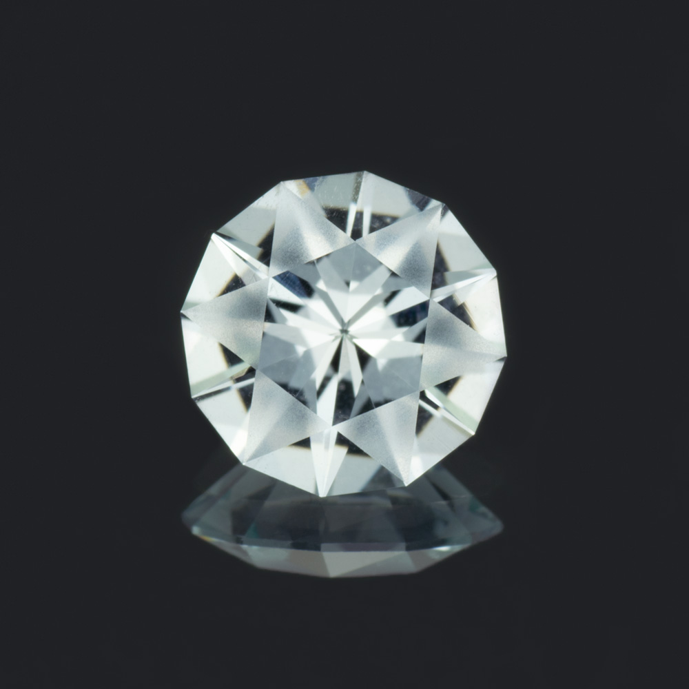 A closeup of a round aquamarine gemstone, cut with frosted main facets.