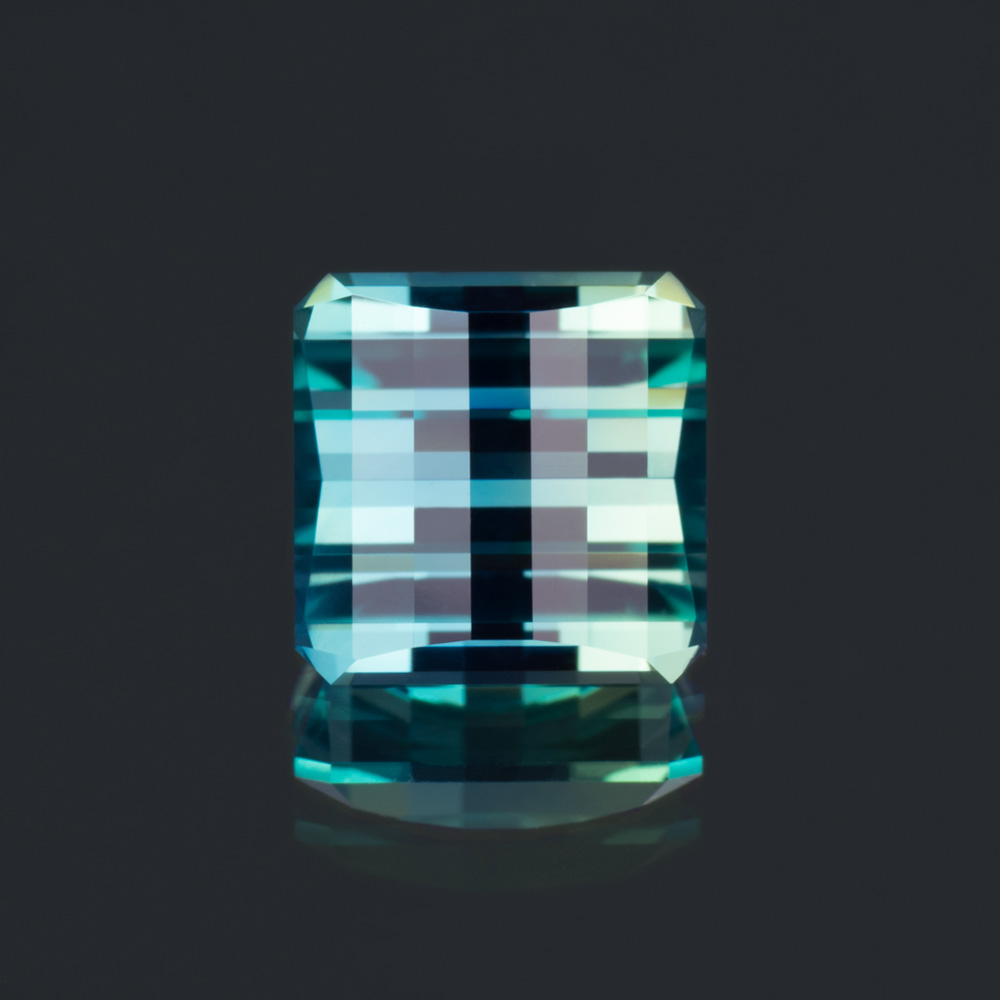 A picture of an opposed bar cut, also known as a pixel cut, teal lab-created sapphire.