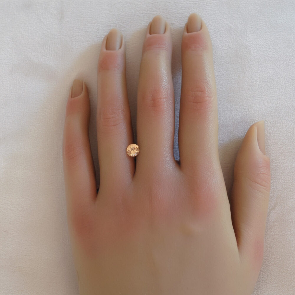 A picture of a round hessonite garnet on a hand.