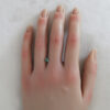 An image of a blue-green Australian sapphire on a hand.