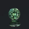 An image of a round blue-green Australian sapphire that weighs 0.71 carats.