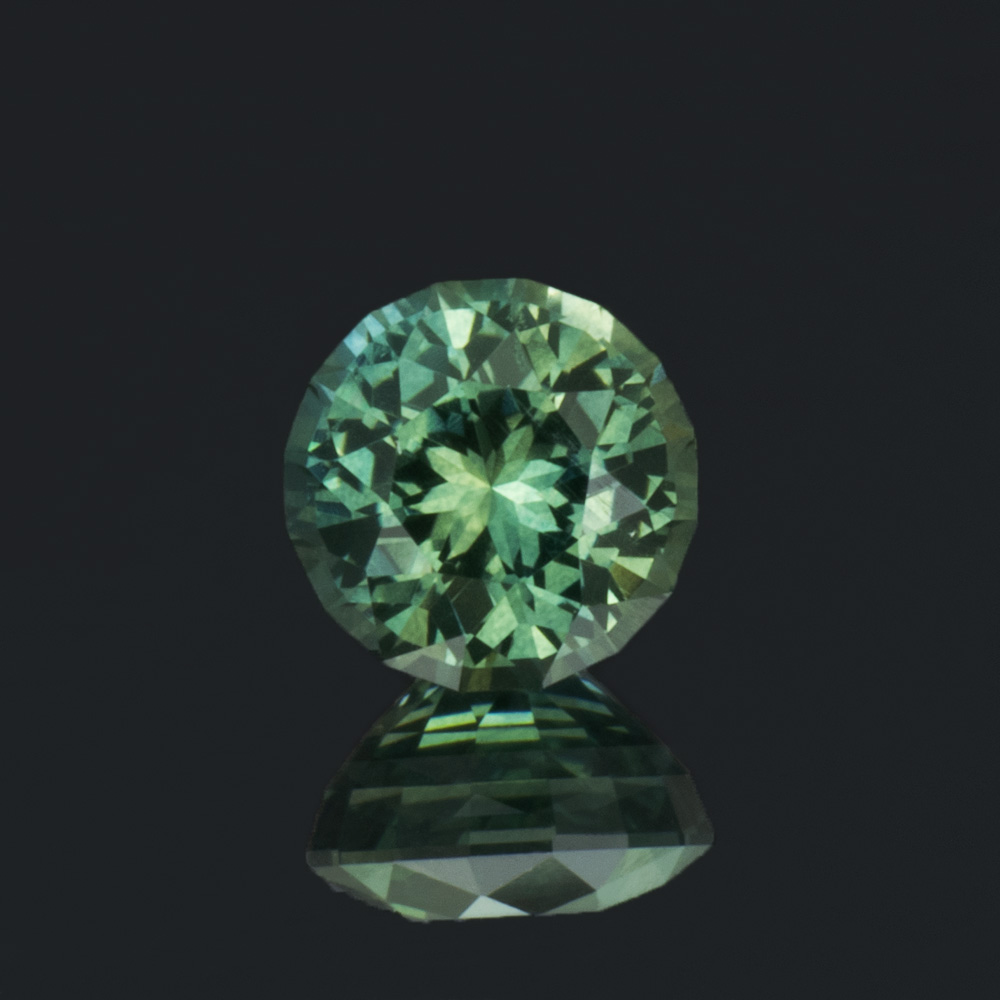 An image of a round blue-green Australian sapphire that weighs 0.71 carats.
