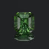 An photograph of a square cut forest-green tourmaline, moderately included.