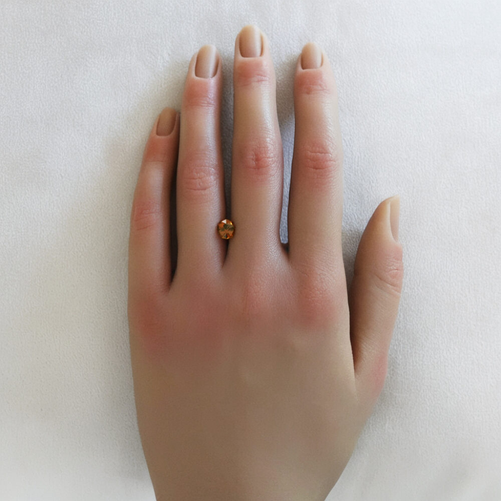An image of an orange hessonite garnet on a woman's hand.