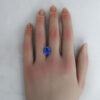 A large 6 carat lab-grown sapphire shown on a hand.